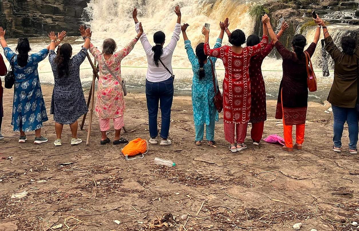 ECHEPURON travellers raising their arms in front of a waterfall near Dhanbad