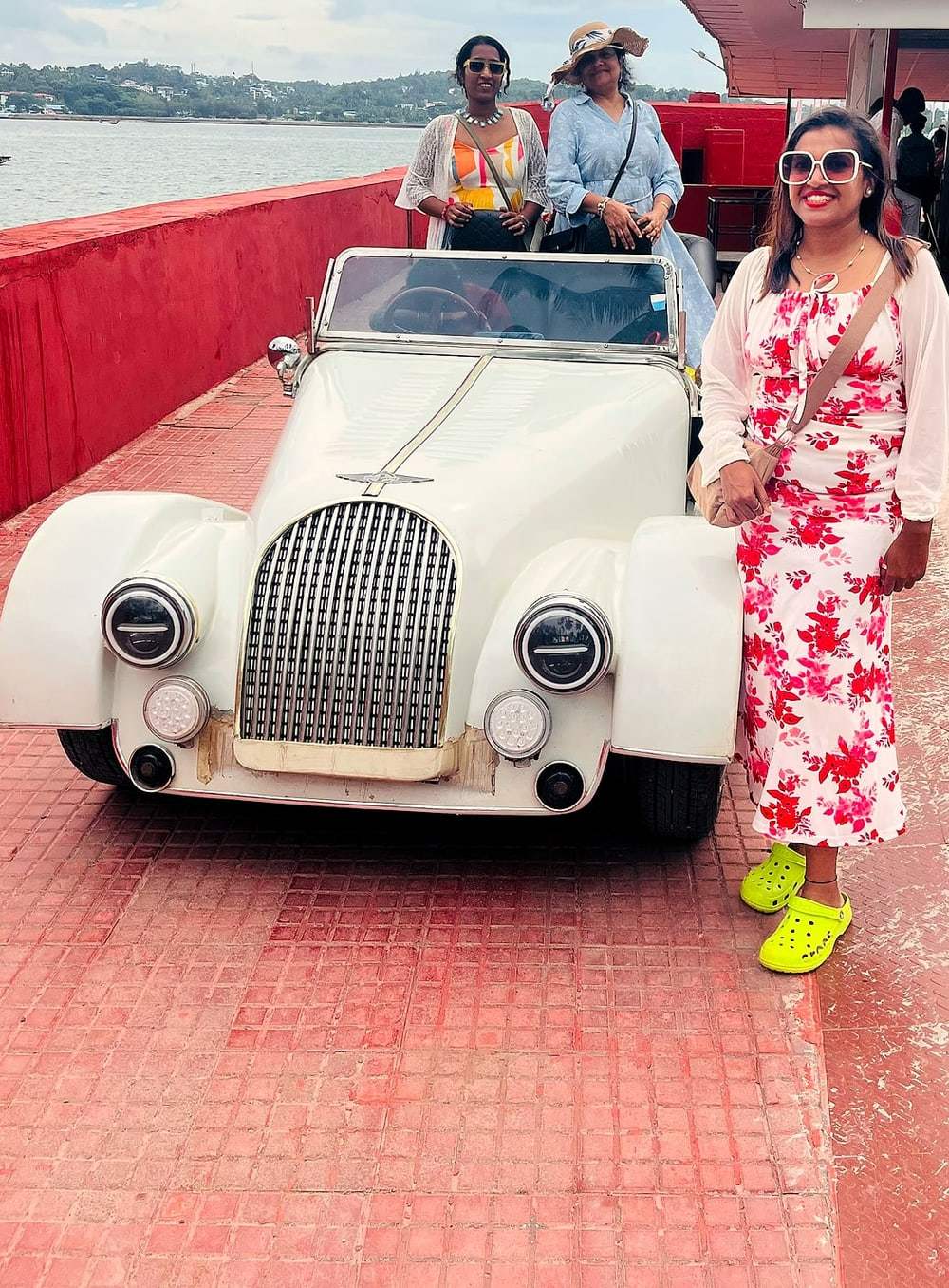 A traveller beside a vintage open-top car on a ferry in the Andaman Islands