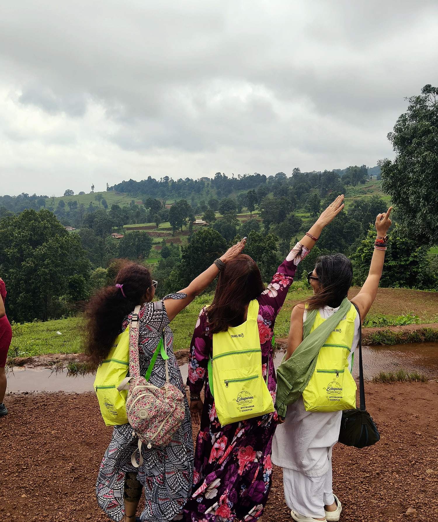 Friends pointing out across green hills from a viewpoint in Mainpat