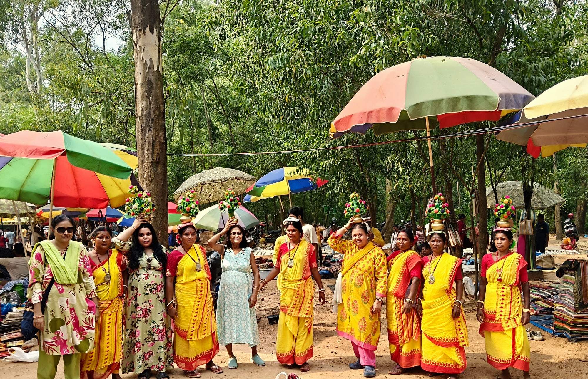 Women in yellow saris performing a folk dance under colourful umbrellas